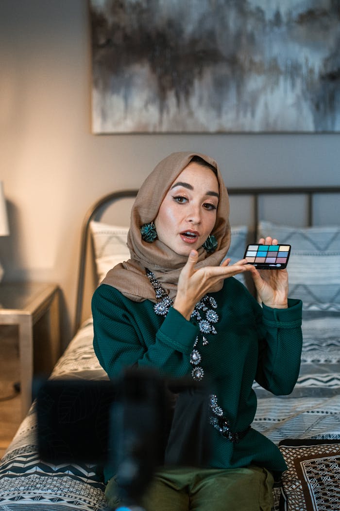 Home A Muslim woman in hijab demonstrates a makeup palette during a tutorial session.