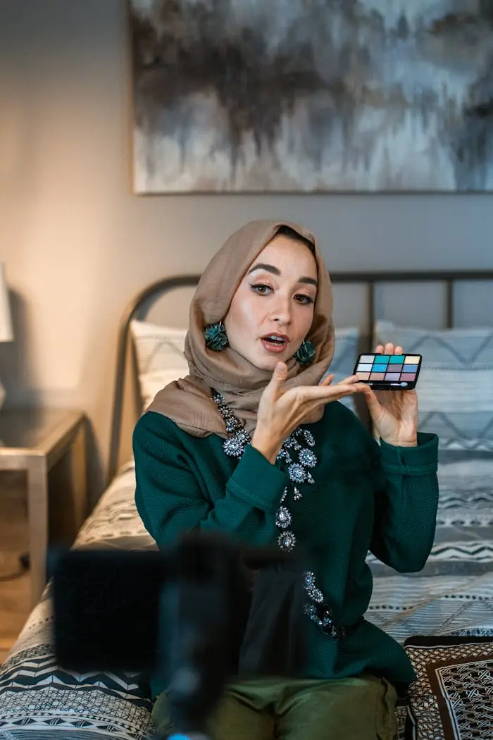 A Muslim woman in hijab demonstrates a makeup palette during a tutorial session.