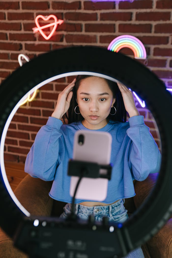 about-01 Asian woman recording a video with a smartphone and ring light for streaming purposes.