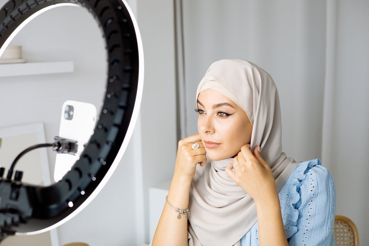 project-03-c Woman in hijab using smartphone and ring light for video recording indoors.
