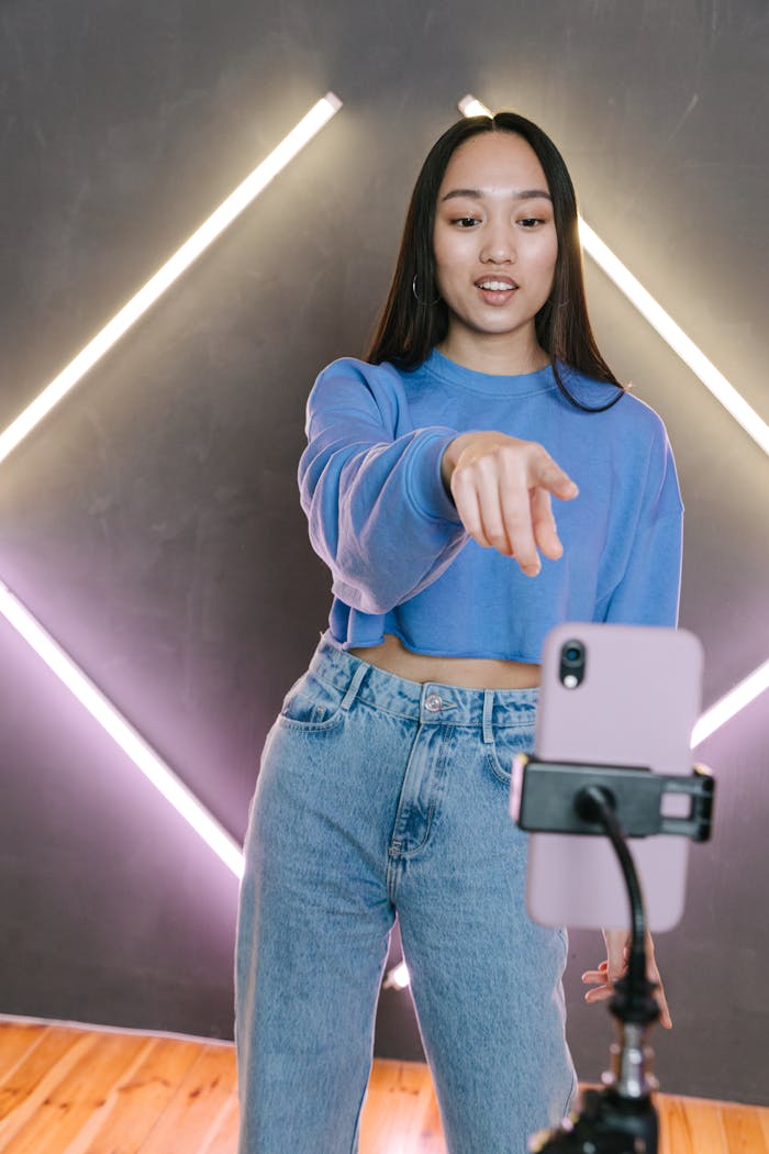 project-01-d Asian woman streaming content using smartphone and tripod in modern setup.