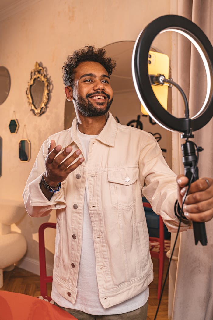 contact-header Smiling vlogger using a ring light in a cozy indoor setting.